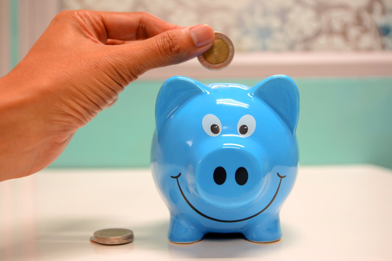 services-04 Hand inserting a coin into a blue piggy bank for savings and money management.