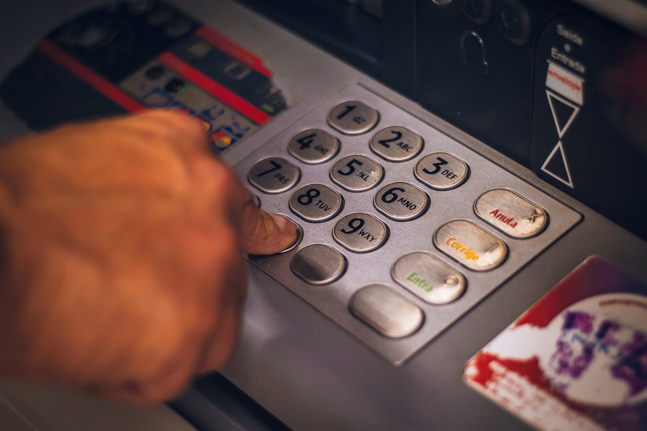 services-02 A hand pressing a button on an ATM keypad in Brasil, emphasizing digital banking.